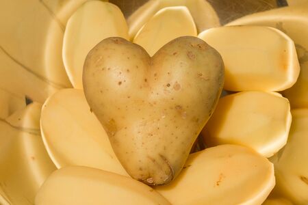 Heart shaped potatoes with other potatos in a bowlの写真素材