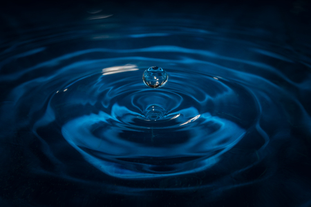 Water drop on waves with blue background and reflectionの写真素材