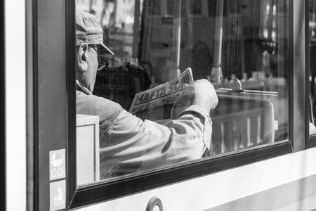Germany, Munich, March 25, 2017, Older turk man is reading a turkish newspaper called hafta sonu in a tramway in munichのeditorial素材