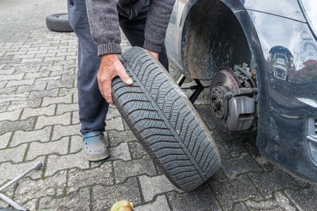 Manually tire change with four-way socket wrenchの写真素材