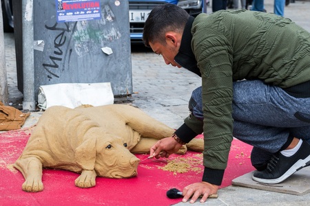Regensburg, Bavaria, Germany, October 24, 2017: Street artist is modeling a dog with sand in the pedestrian zone in Regensburg, Germanyのeditorial素材