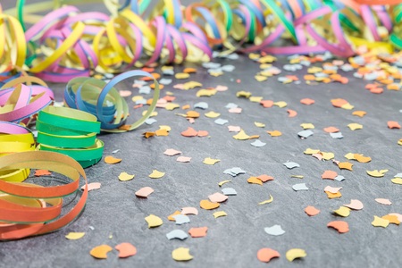 Paper streamer and confetti as carnival decoration on a slateの写真素材