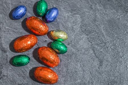 Colorful chocolate easter eggs in front of gray background