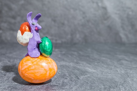 Easter bunny made of purple play dough in front of gray backgroundの写真素材