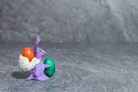 Easter bunny made of purple play dough in front of gray backgroundの写真素材