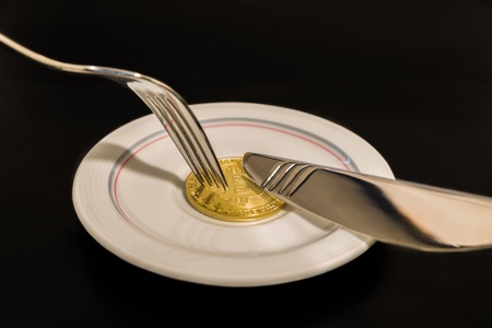 Gold coin bitcoin on plate with fork isolated on black backgroundの写真素材