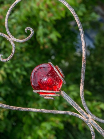 Heart-shaped garden plug decorated with a red glass ballの写真素材