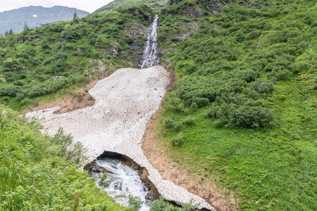 Remains of the ice cover and snow cover over a summer mountain stream, Austriaの写真素材