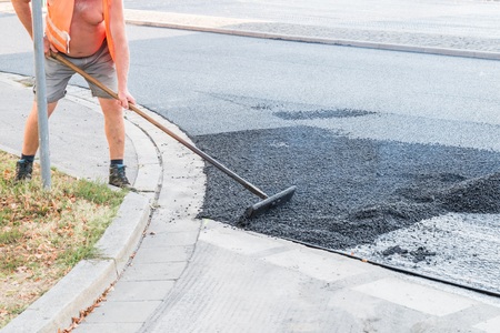 Road workers distributing the hot asphalt with shovels on the road, Germanyの写真素材