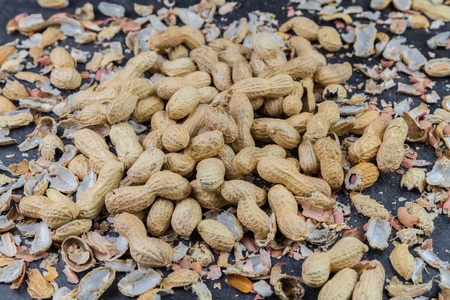 Many peanuts and peanut shells distributed on a kitchen worktop