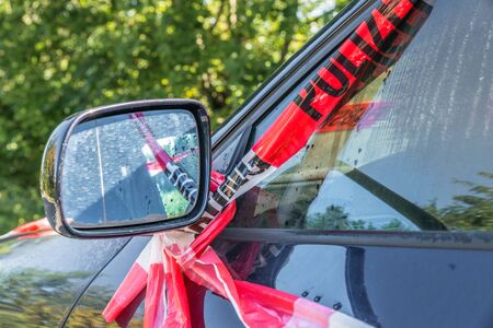 Side mirror of a car after a violent accident with police barrier tape in red and white with the...