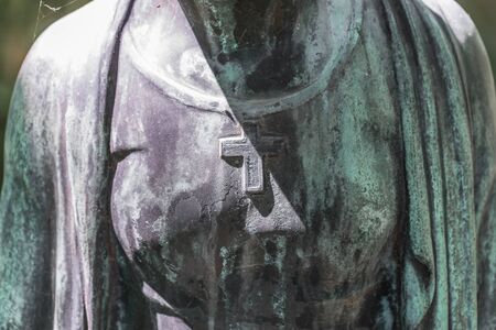 Detail image of a female breast with cross of a bronze statue of a woman in a park, Germanyの写真素材