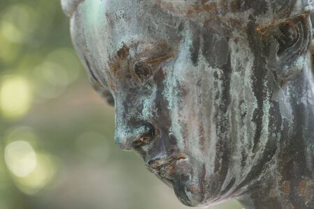Close up of a female bronze statue of a woman with short hair with cross and cardigan in a park, Germanyの写真素材