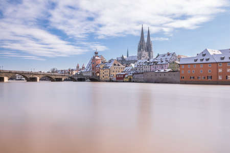 Sunset during flood of Danube river in winter 2021 in Regensburg with view of cathedral the old town and flooded promenade and the stone bridge, Germanyの写真素材
