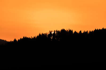 Close up of sun during sunset over horizon with mountain hill landscape in foreground, Germanyの写真素材
