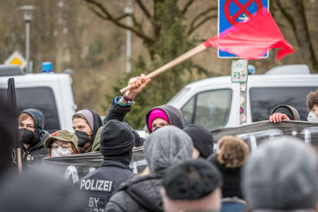 Regensburg, Bavaria, Germany, January 26, 2022: Demonstrators of Antifa left antifascists at an anti-Corona demonstration in Regensburg with banner shielded by police with red flag, Germanyのeditorial素材
