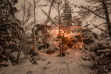 Golden sparks spray at night in the snow on mountain the sparks by glowing steel wool thrown in a circle, Germanyの写真素材