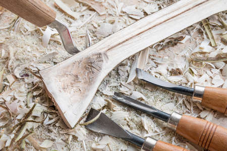 Self carved wooden spoon cooking spoon pan scraper fork worked with knife tool on a workbench with wood chips, Germanyの写真素材