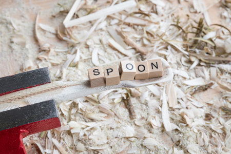 Self carved wooden spoon cooking spoon pan scraper with the word - SPOON - on a workbench with wood chips, Germanyの写真素材