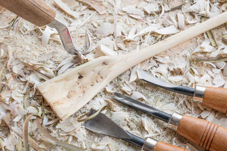 Self carved wooden spoon cooking spoon pan scraper fork worked with knife tool on a workbench with wood chips, Germanyの写真素材