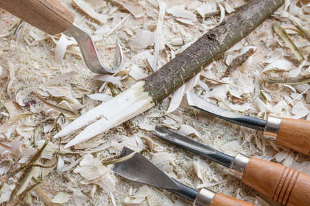 Self carved wooden spoon cooking spoon pan scraper fork worked with knife tool on a workbench with wood chips, Germanyの写真素材