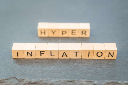 The word Inflation and Hyper in the background text written on a slate with a wooden cube.