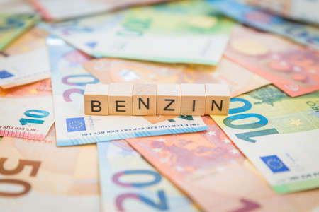 The word Benzin - in German for Gasoline - written on banknotes Euro notes with wooden cubesの写真素材