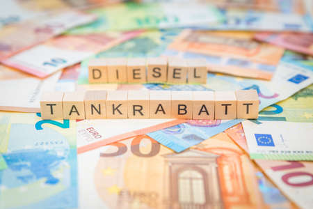 The word Tankrabatt - in German for Fuel discount - and Diesel - in German for Diesel - in the background on banknotes Euro notes written with wooden cubes Textの写真素材
