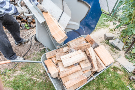 Close up of a wheelbarrow fully loaded with logs working and sawing wood, Germanyの写真素材