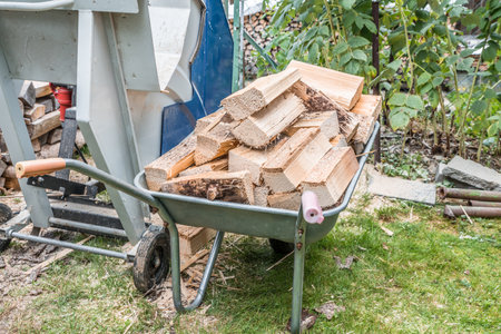 Close up of a wheelbarrow fully loaded with logs working and sawing wood, Germanyの写真素材