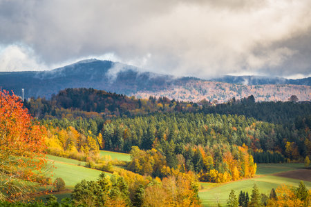 View of Mount Lusen in autumn during stormy weather with clouds and sunbeams shining on the autumn landscape in Lower Bavaria, Germanyの写真素材