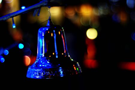 Blurred Christmas lights in the night with a bell on a black background, bokeh, Light bokeh abstract.の写真素材