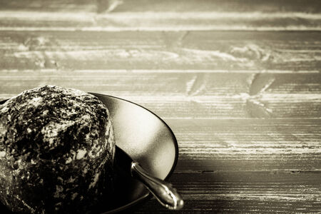 A plate with bread an a knife on a wooden table.