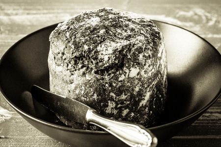 A plate with bread an a knife on a wooden table.の写真素材