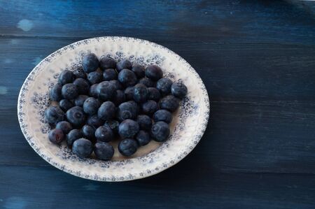 Old plate with blueberries on vintage blue backgroundの写真素材