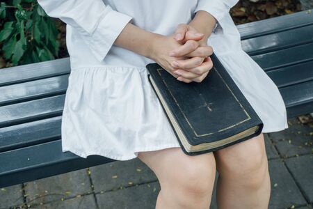Woman hands praying with a bible in her knees outdoorsの写真素材