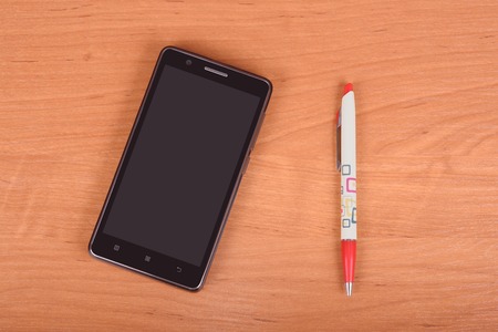 Black cellphone on wooden background