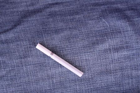 Closeup photo of cigarette on a blue jeans backgroundの写真素材