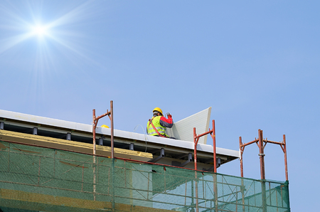 Man working on the new roof on a sunny dayの写真素材