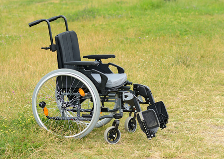 Empty used wheelchair standing on the green grassの写真素材