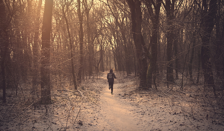 Man running in the winter forest in morning lightの写真素材