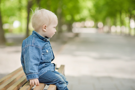 Little boy sitting on the bench in the parkの写真素材