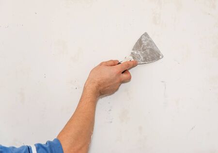 Painting worker repair wall using a paint spatula hand. Closeup photoの写真素材