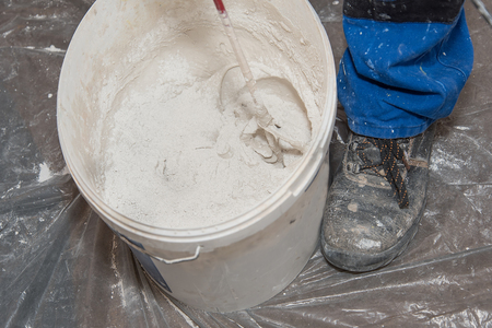 Paint mixer and bucket on covered floor の写真素材
