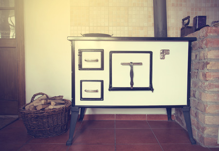 Vintage house cooking stove in a kitchen, with firewood in basketの写真素材