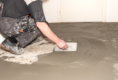 Worker applied adhesive for ceramic tiles in construction