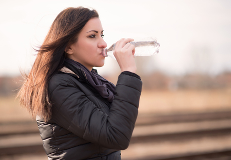 Young woman drinking water. Closeup photoの写真素材