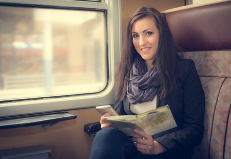 Young, pretty woman in train and hold a mapの写真素材