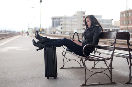 Young traveler woman waiting for a train at the stationの写真素材