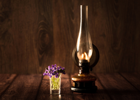 Spring concept with violet and oil lamp on wooden backgroundの写真素材